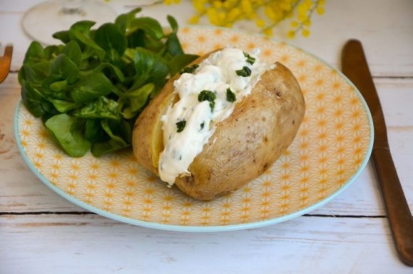 Pomme de terre au four garnie de crème et ciboulette, accompagnée de salade verte.